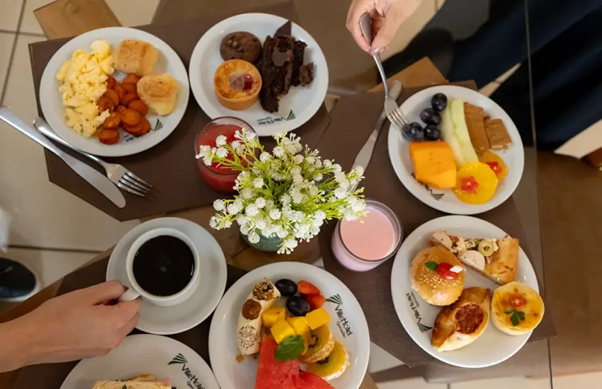 Mesa de café da manhã com pratos variados e sucos naturais no Ville Hotel Gramadão